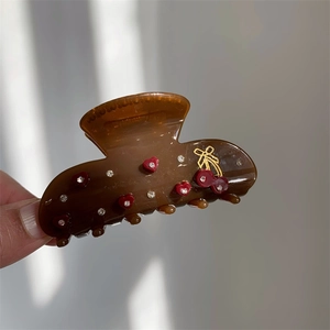 Detail einer braunen Haarklammer mit roten Herzen und goldenem Kirsch-Motiv