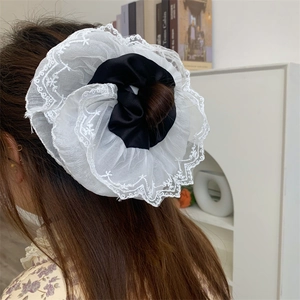 Macro shot of large double-layer lace scrunchie with white embroidery and black satin details