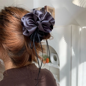 Détail macro du chouchou en satin gris anthracite avec rubans sur un modèle féminin