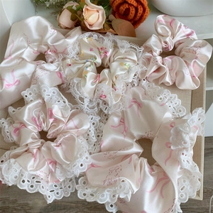 Close-up of pink and white satin hair scrunchies with elegant lace trim and bow patterns