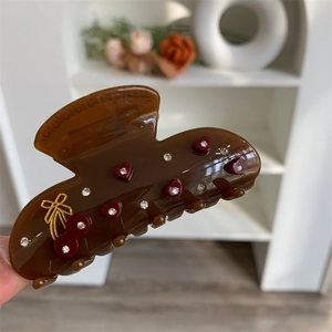 Nahaufnahme einer glänzenden braunen Haarklammer mit roten Herzmustern und Kristalldetails
