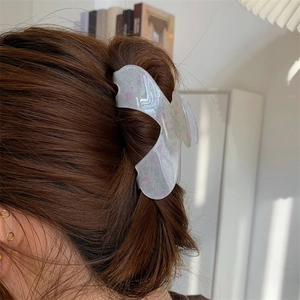 Detail of cream acrylic hair claw clip with pink flowers worn on long hair