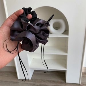 Détail d'un chouchou en satin noir brillant avec de longs rubans élégants à la main
