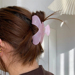 Detail view of pink butterfly hair claw clip with glitter finish on model hair
