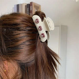 Detail der Haarspange in Creme mit roten Strass-Herzen getragen im braunen Haar