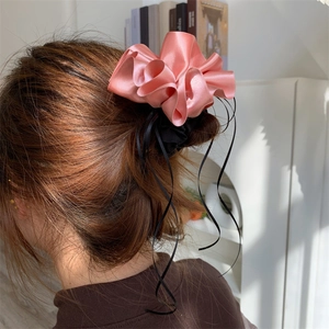 Chouchou fleur en satin rose avec de longs rubans noirs sur une queue de cheval