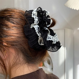 Detailed view of black pleated chiffon hair scrunchie with white floral lace trim edges