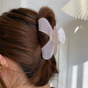 Floral acrylic hair claw clip with pink resin bow shape worn on brunette long hair