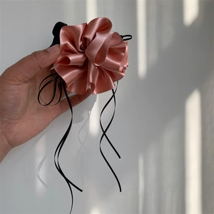 Gros plan d'un chouchou fleur en satin rose avec d'élégants rubans noirs et texture douce