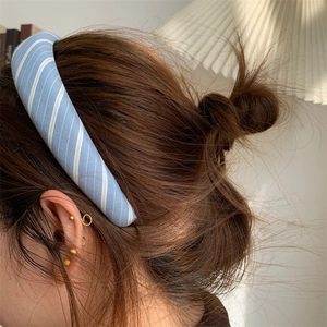 Close-up of light blue and white checkered knit headband on model with gold earrings