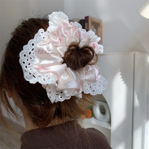 Close-up of pink satin hair scrunchie with white lace trim worn on long hair