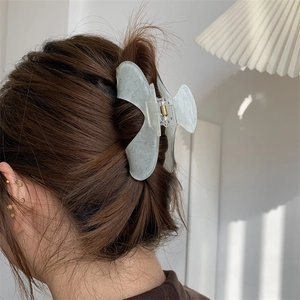 Detail of a large acrylic translucent green floral claw clip styling on long hair
