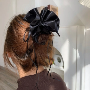 Détail d'un chouchou élégant en satin noir avec ruban attaché dans un chignon chic
