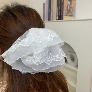 Detailed view of an oversized ivory lace scrunchie styled on a woman's ponytail hair