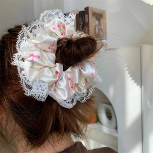Elegant satin hair scrunchie with pink floral pattern and white lace trim detail