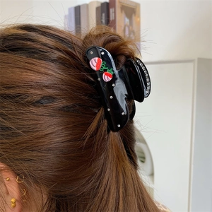 Detail von süßer Erdbeer-Haarklammer mit Strasssteinen an einer Haarknoten-Frisur