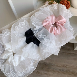 Detailed view of large lace scrunchies in pink, black, and white satin and embroidery
