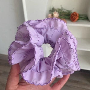 Detail of purple hair scrunchie with ruffled wave edges and deep violet embroidery stitching