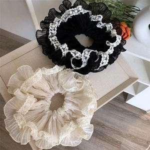 Close-up of black and beige lace scrunchies with pleated mesh texture on display