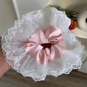 Close-up of pink satin scrunchie with layered white lace embroidery detail and volume