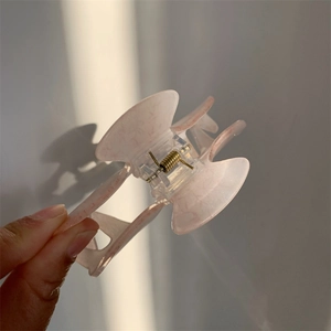 Detail view of pink translucent acrylic hair claw clip with golden metal spring