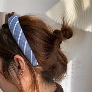 Detail view of blue and white striped fabric headband worn by a model in soft light