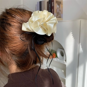 Gros plan d'un chouchou en satin blanc crème avec ruban noir sur un chignon bas