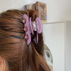 Detailaufnahme der lila Haarklammer mit roten Kristallherzen im Haar des Models