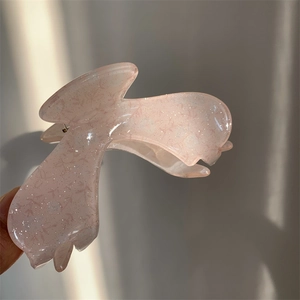 Macro detail of translucent pink acrylic claw clip with glitter and floral prints