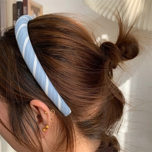 Detail of light blue checkered headband worn by model with gold earrings and soft lighting
