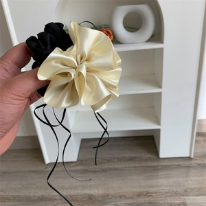 Gros plan détaillé de chouchous à fleurs en satin champagne et noir avec longs rubans