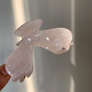 Detailed view of a light pink acrylic floral claw clip with pearlescent finish and patterns