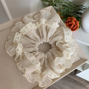 Close-up of cream lace pleated hair scrunchie with layered texture on a tray