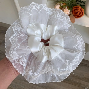 Detailed view of oversized white lace and satin scrunchie with layered embroidery