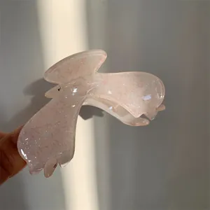 Detail of light pink acrylic flower hair claw clip with subtle glitter finish
