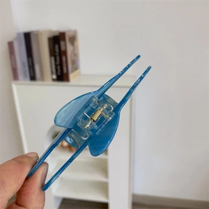 Détail d'une pince à cheveux bleue translucide avec un ressort en métal doré