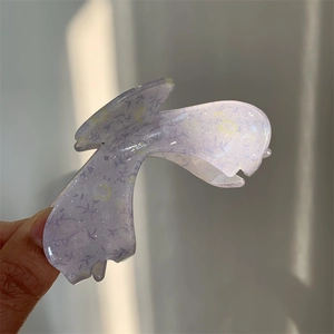 Detailed view of purple acrylic floral hair claw clip with gold glitter in natural light