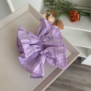 Elegant purple chiffon scrunchie with ruffled lace edges on a stylish display tray