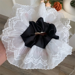 Detail of oversized lace scrunchie with black satin center and white embroidered tulle