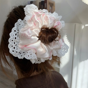 Pink satin scrunchie with lace trim and bow pattern shown on a bun in a home setting