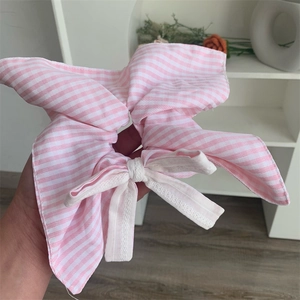 Close-up of pink and white striped cotton scrunchie with lace bow detail and soft texture