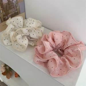 Detailed view of large polka dot scrunchies in pink and beige jacquard fabric textures