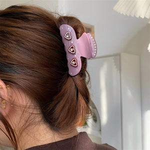 Details einer lavendelfarbenen Haarspange mit Herz-Strasssteinen auf braunem Haar