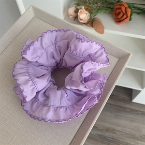 Detailed close-up of lavender pleated hair scrunchie with scalloped stitched edges