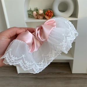 Macro shot of oversized pink satin scrunchie with layered white lace embroidery detail