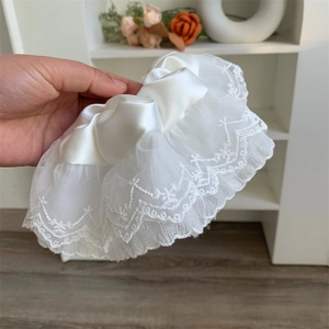 Detail of white oversized lace scrunchie showing delicate embroidery and satin fabric