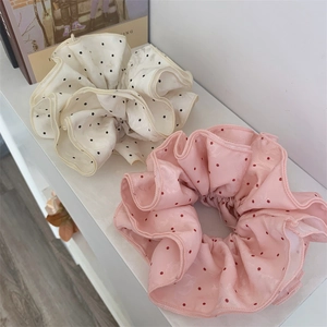 Close-up of pink and beige polka dot oversized hair scrunchies with soft fabric texture