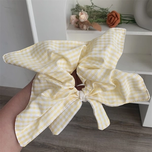 Detailed view of yellow and white checkered cotton scrunchie with a large double bow