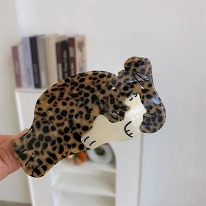 Détail de la pince à cheveux motif léopard en résine en forme d'animal tenue à la main