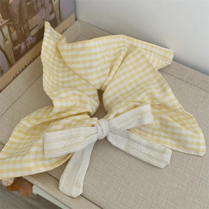 Detail of yellow plaid bow scrunchie with delicate white lace trim and cotton texture